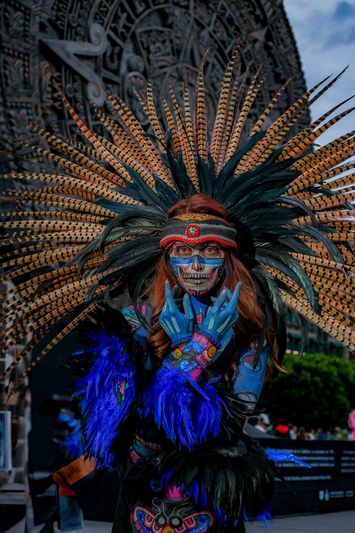 Vibrant Day of the Dead costume with feathers, skull makeup, and intricate design in a festive outdoor setting.